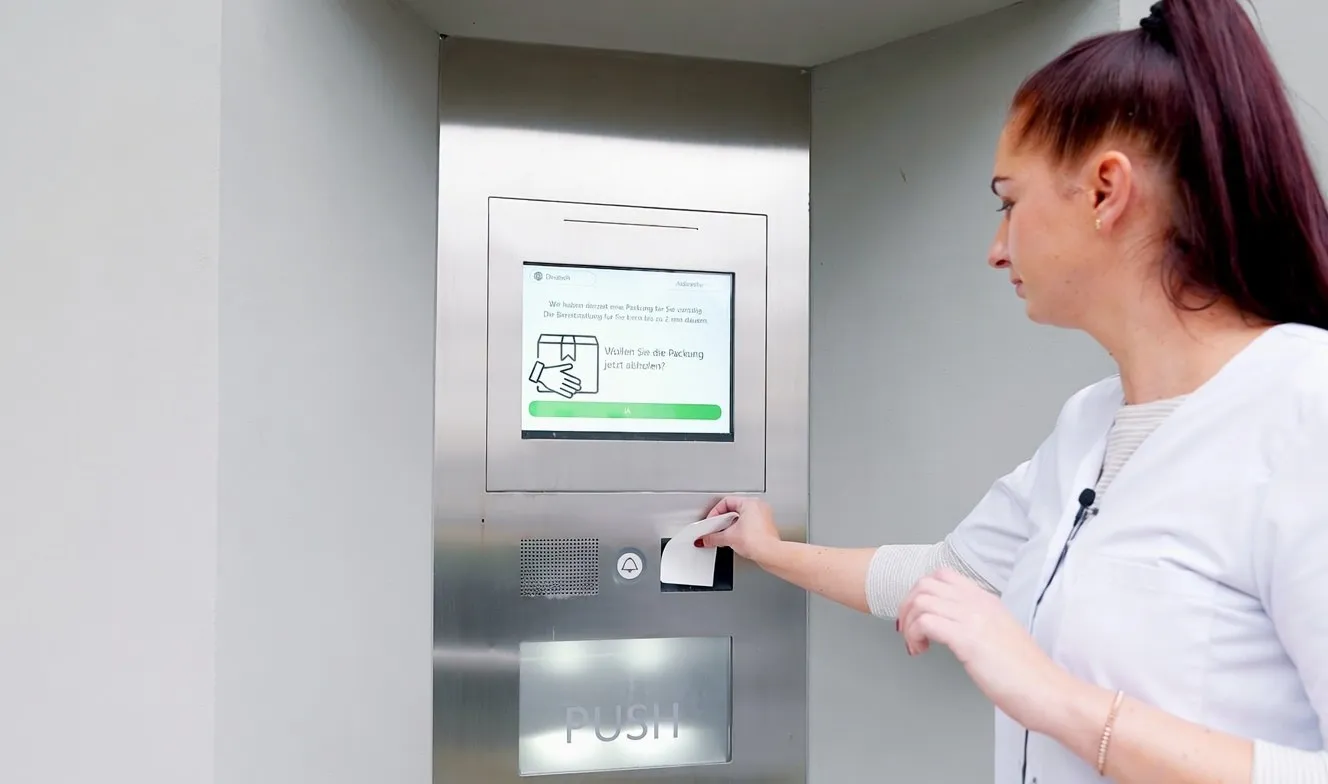 A member of staff using the screen of the pick-up terminal, holding the collection code