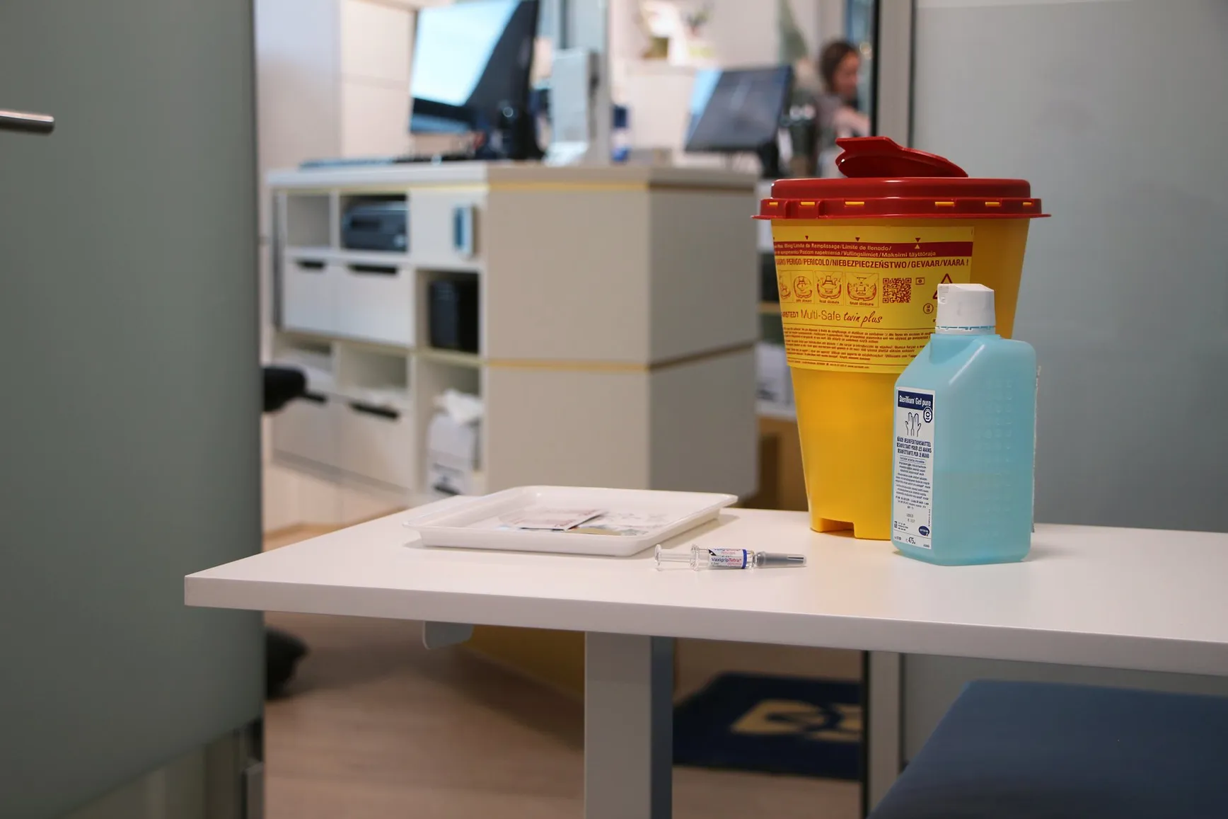 Prepared vaccination materials on the table in the consulting room, with the disposal container beside them