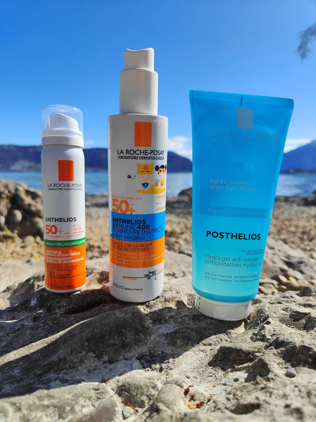 Three sun protection products on a stone by Lake Zug