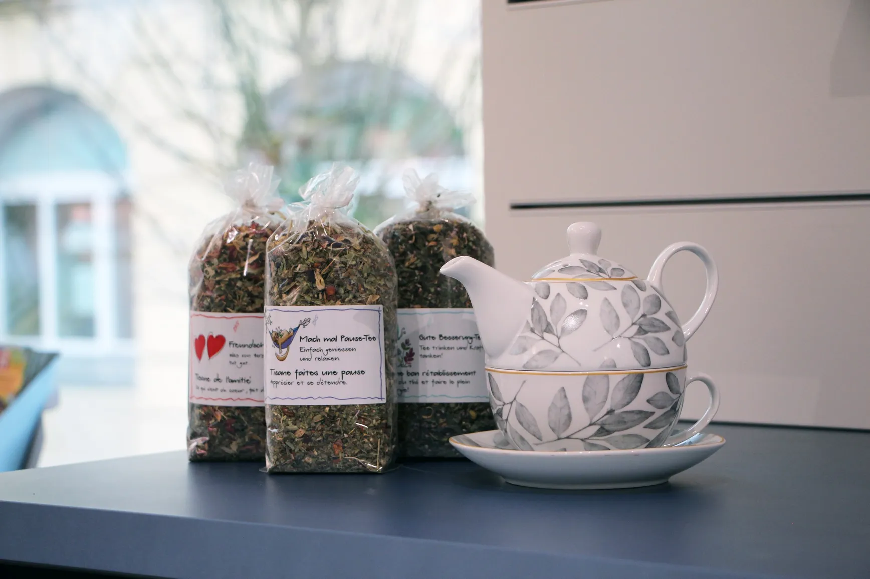 Loose herbal teas in bags next to a glass teapot